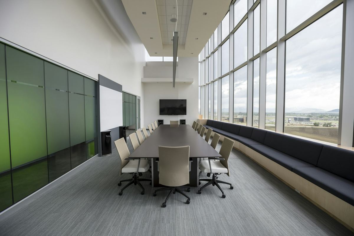 An empty conference room with a long table and floor-to-ceiling windows