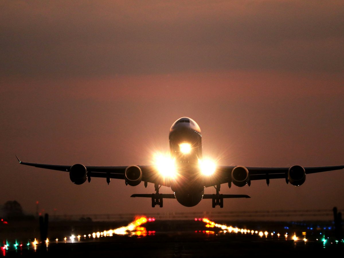 A passenger jet taking off at dusk with its landing lights on