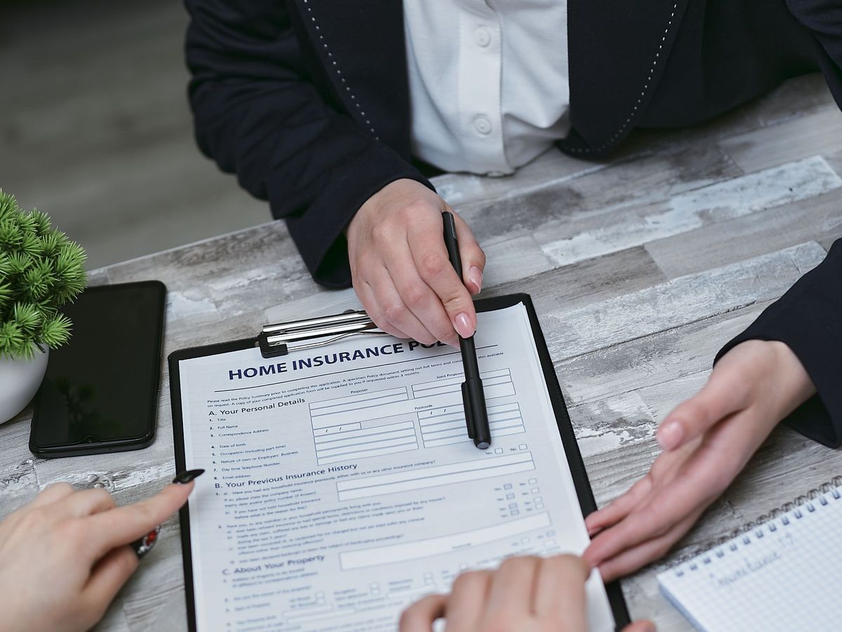An agent and two clients reviewing a home insurance policy on a clipboard